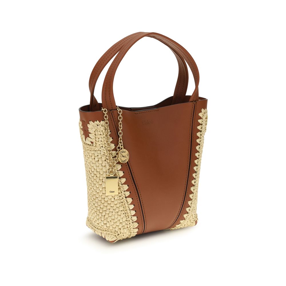 Side view of Chloé Spin Tote Bag Small in Clay Brown Raffia & Leather from The Exclusive Line Singapore.
