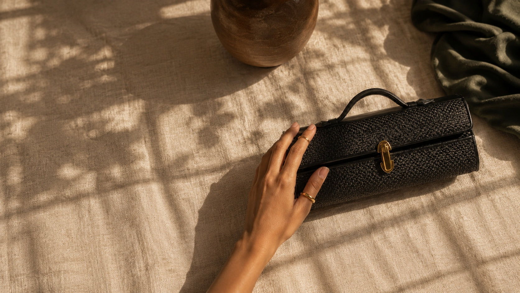 Savette Slim Symmetry Pochette in black raffia with gold horseshoe closure — available at The Exclusive Line Singapore
