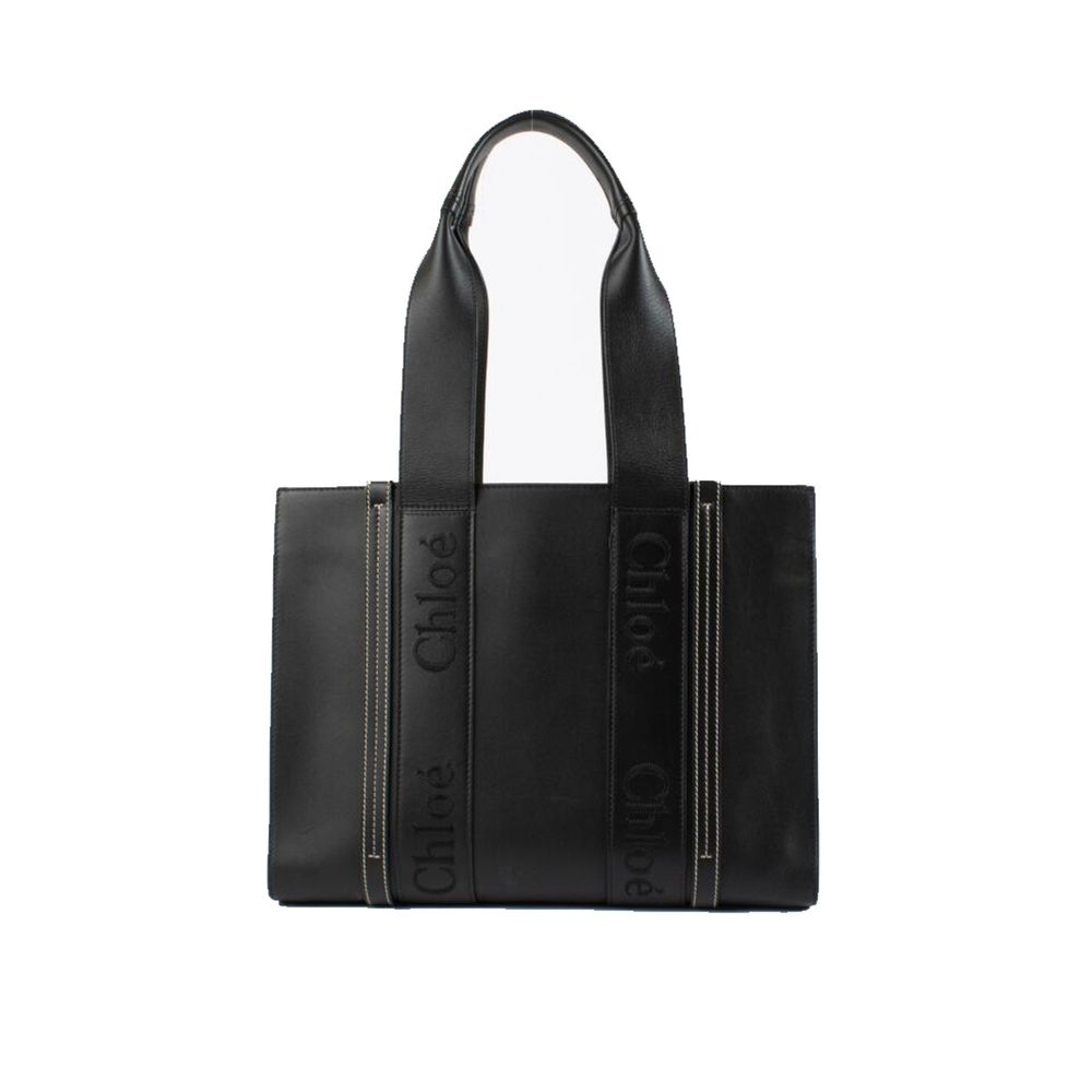 Chloé Large Woody Tote Bag in black shiny calfskin leather featuring vertical logo straps on a clean white background from The Exclusive Line Singapore.