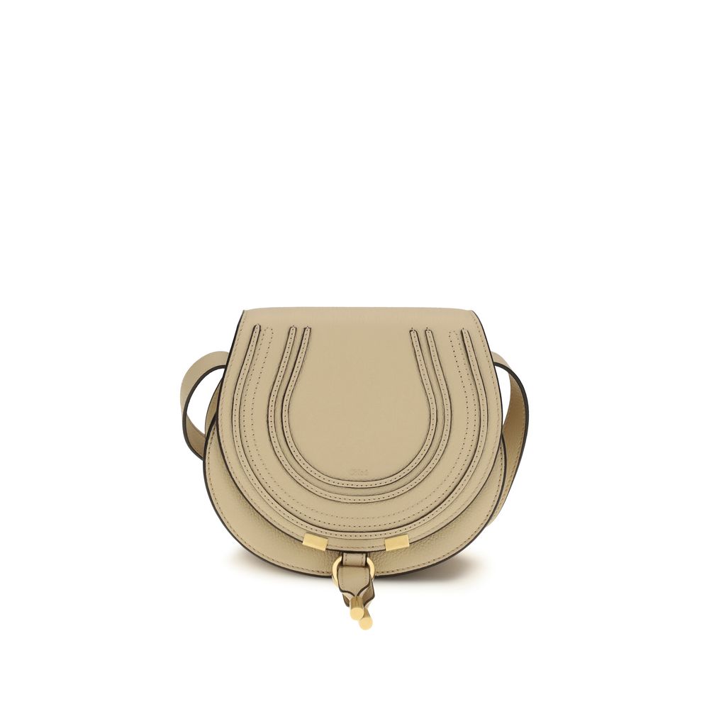 Close-up of Chloé Marcie Small Saddle Bag in petal beige grained leather showing decorative saddle stitches, gold metal details, and the hanging leather tassel.