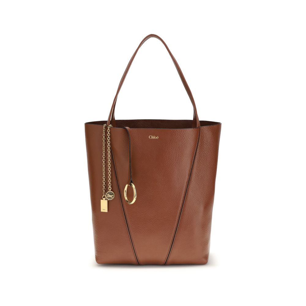 Chloé Spin tote bag in blushy brown shiny grained cowhide featuring dual top handles, a graphic silhouette, and a gold-tone chain with the signature Horse Medal from The Exclusive Line Singapore.