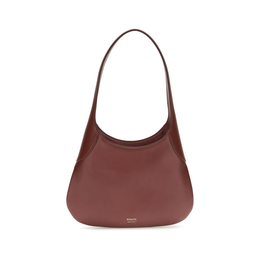 Profile view of the oxblood Khaite Joan Small Hobo Bag in smooth calfskin leather, highlighting its slouchy silhouette and integrated shoulder strap.