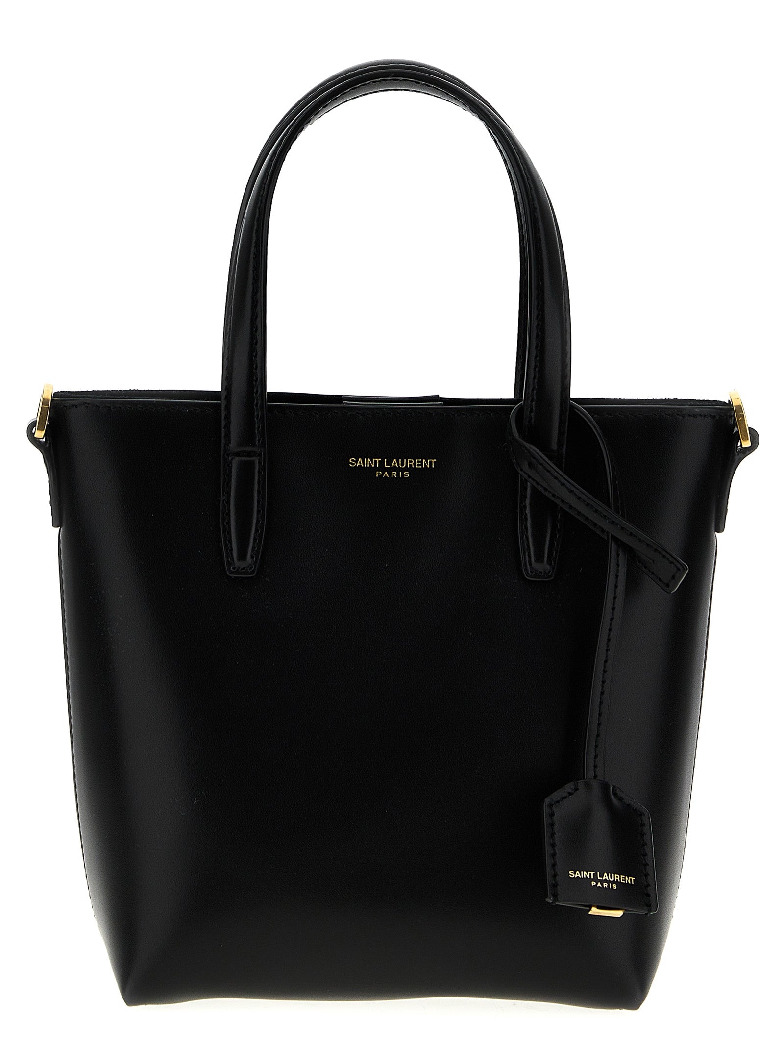 Saint Laurent Toy Mini Shopping tote bag in structured black box leather featuring flat top handles and a hanging bronze CASSANDRE charm from The Exclusive Line Singapore.