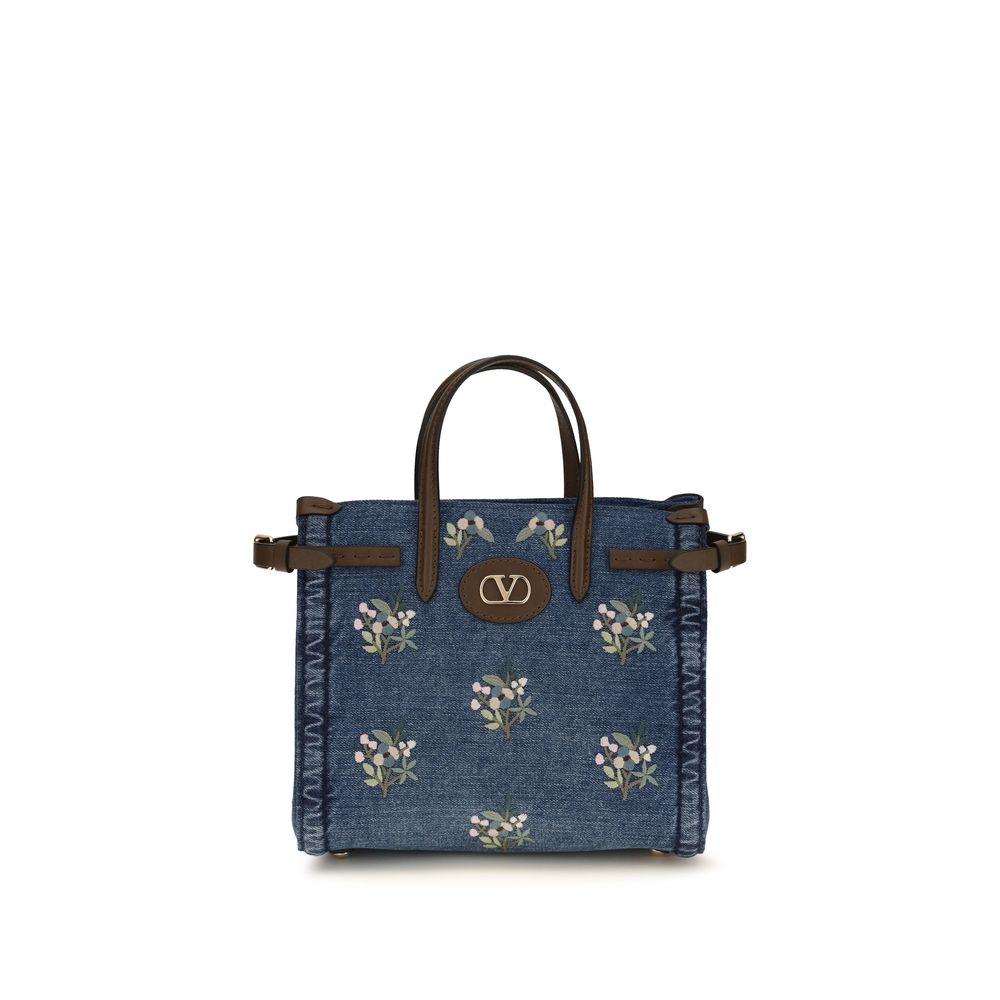 Valentino Garavani Antibes small denim shopping bag with floral embroidery, leather handles, and gold VLogo hardware.